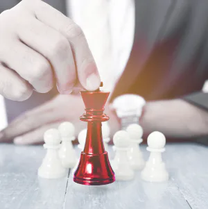 Werknemer plaatst een rode schaakkoning tussen witte pionnen als symbool voor strategisch leiderschap.